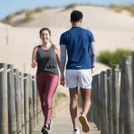 A couple enjoys jogging on a sunny beach boardwalk in Portugal, capturing a moment of fitness and leisure.